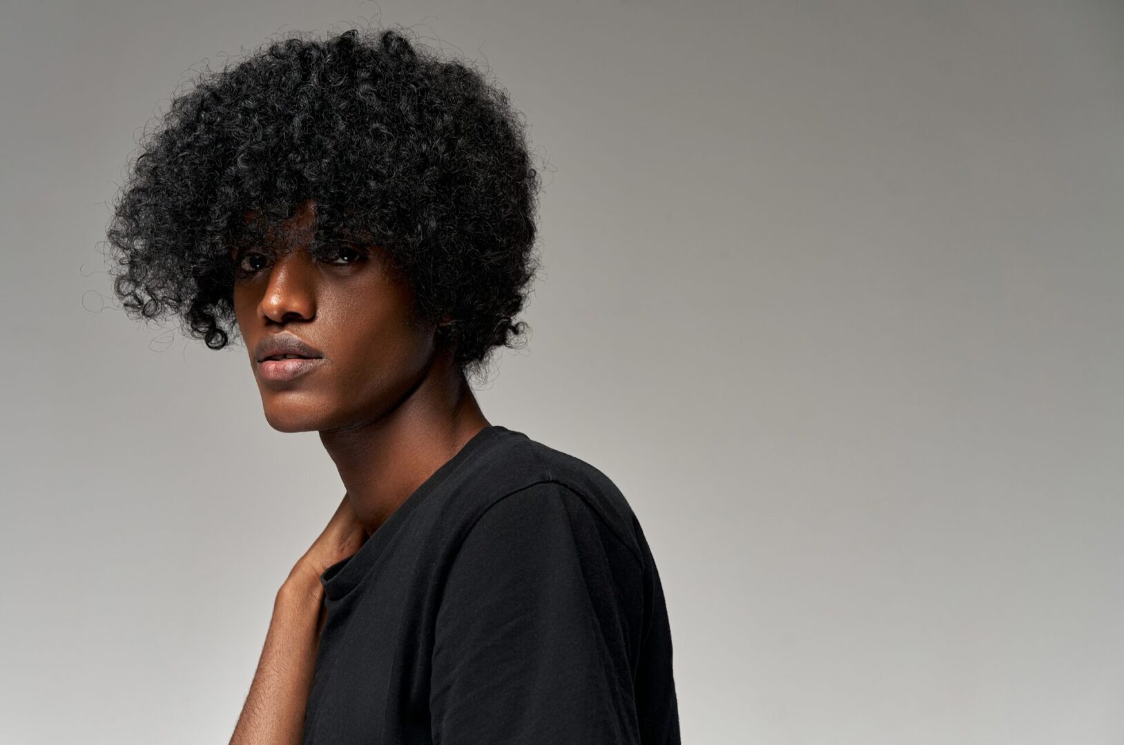 Portrait,Of,Young,African,American,Male,Model,Isolated,On,Gray A man with black hair and wearing a black shirt.