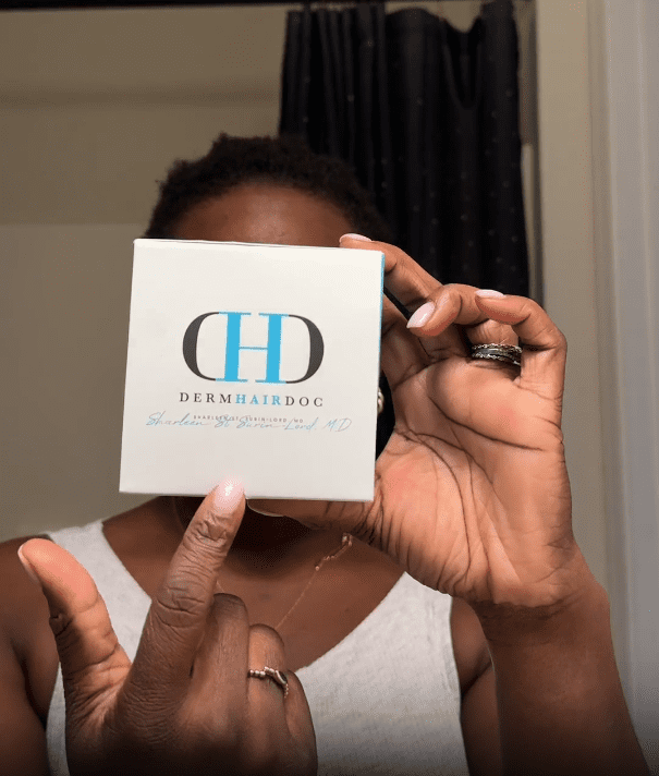 Person holding DermHairDoc product box.
