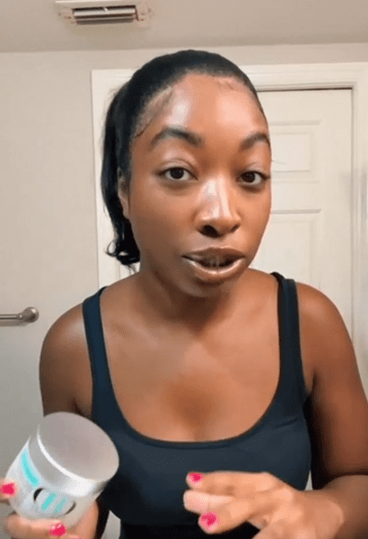 Person holding a skincare product in bathroom.