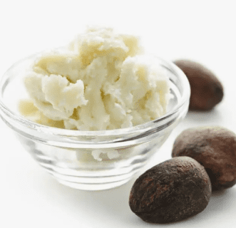 Shea butter in glass bowl with nuts.