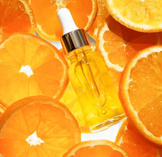 Serum bottle surrounded by fresh orange slices.