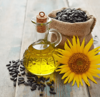 Sunflower oil, seeds, and flower on table.